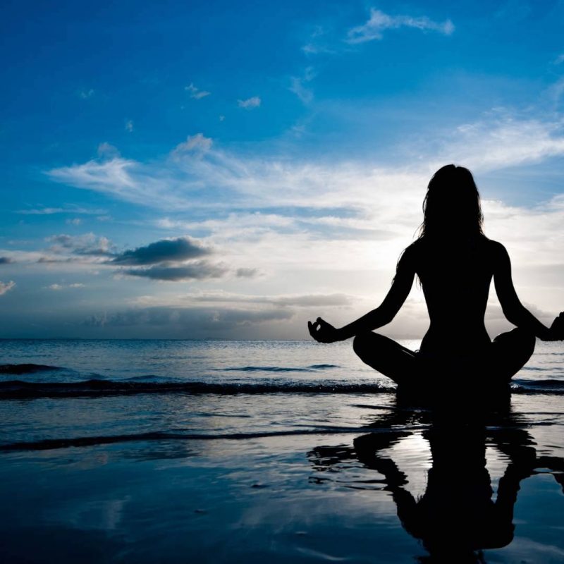 Woman Meditating by the Sea with Beautiful Sky View