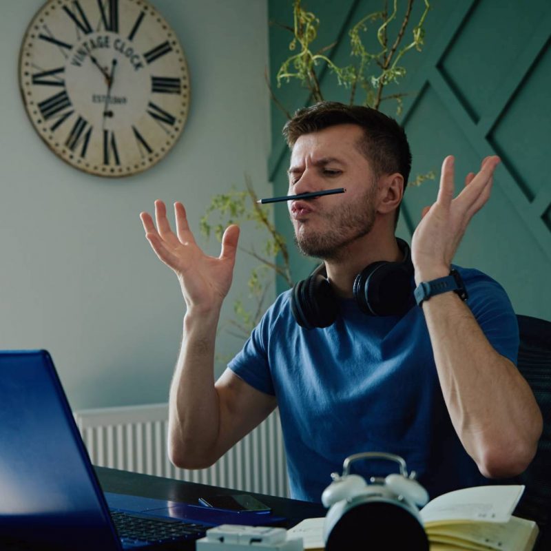 Man Acting Silly and Procrastinating at Work Desk Bored