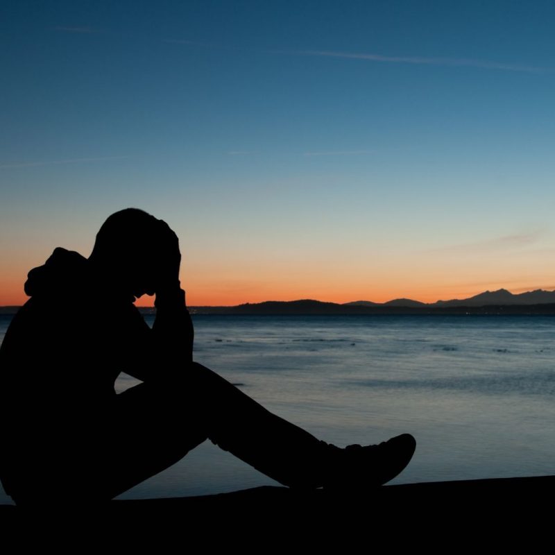 Man with Hands on Head Frustrated Sitting on a Mountain with View