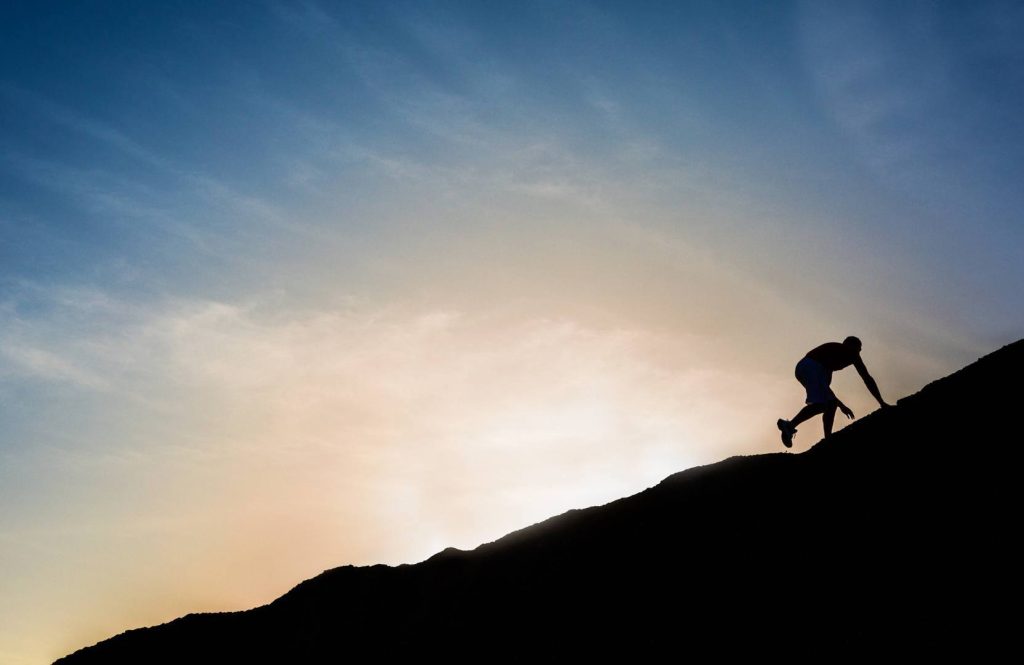 Man Motivated Climbing Up Steep Hill