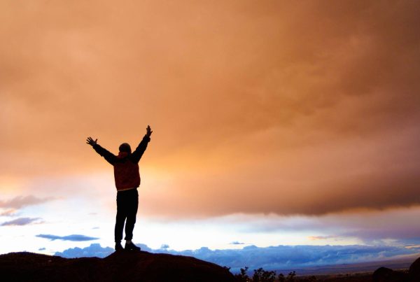 Inspired Man Standing on Mountain with Hands Up with Beautiful View