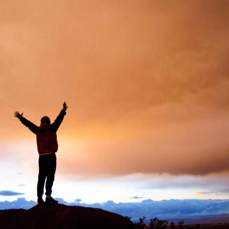 Inspired Man Standing on Mountain with Hands Up with Beautiful View