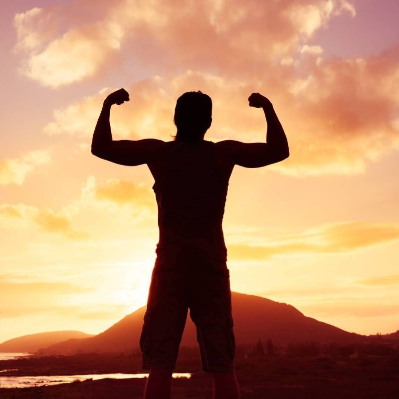 Powerful Man Standing Flexing Muscles with View of Mountain with Sunset