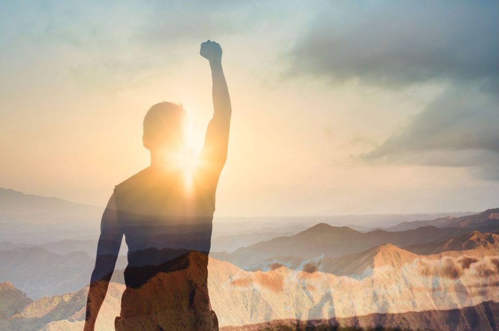 Man Standing with Mountain View Victorious with Fist in Air