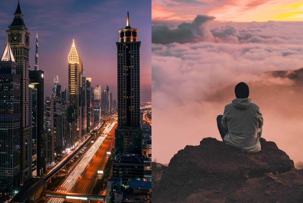 Photo of Busy City Compared to a Man Sitting on a Rock with View of Clouds and Mountain