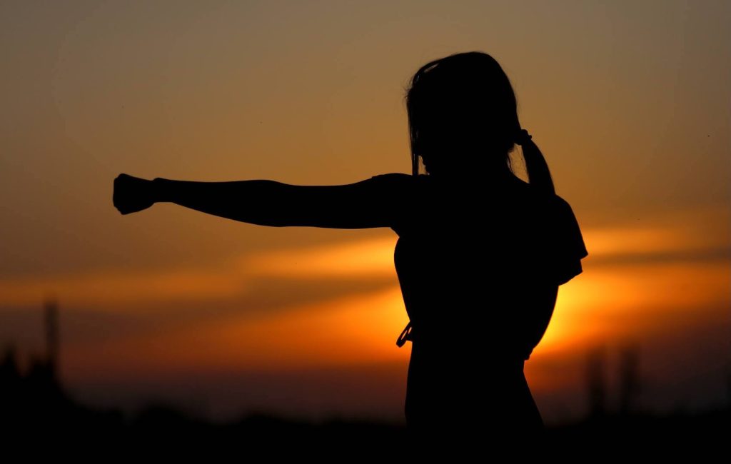 Powerful Woman Punching the Air with Sunset in the Background