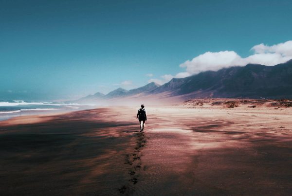 Man Walking on Beaching Taking a Journey Through Life with Blue Sky View and Mountains