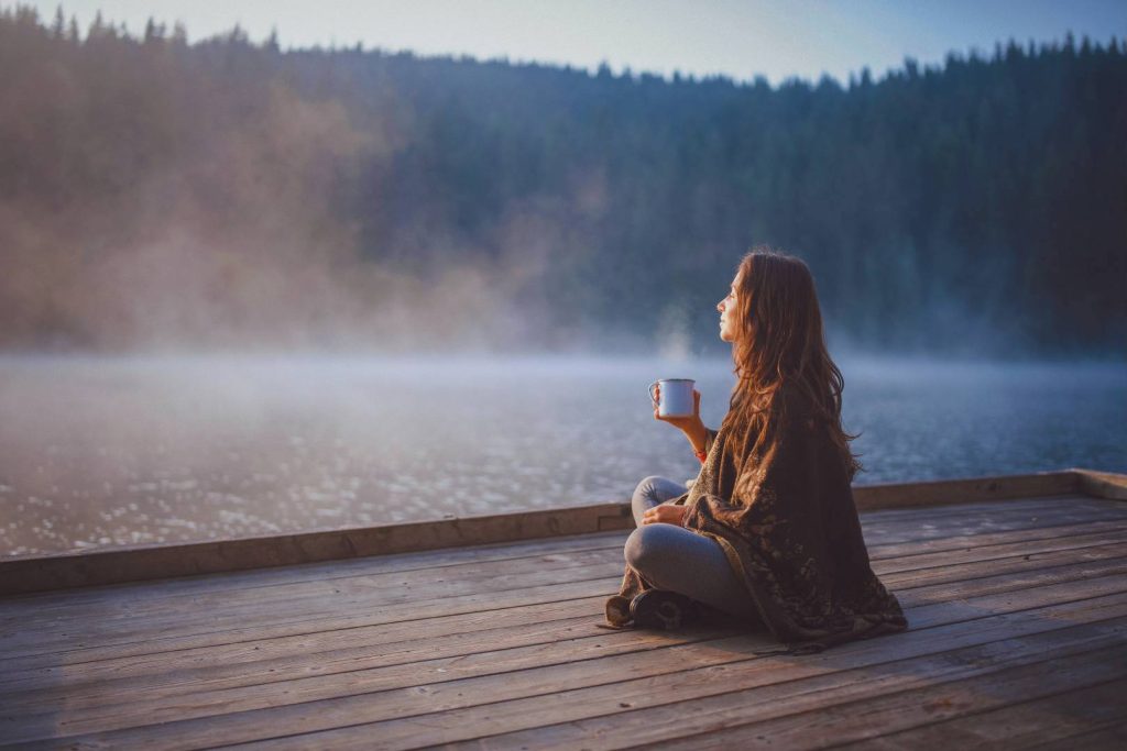 Woman Sitting Drinking a Cup of Tea Relaxed with Beautiful View of River