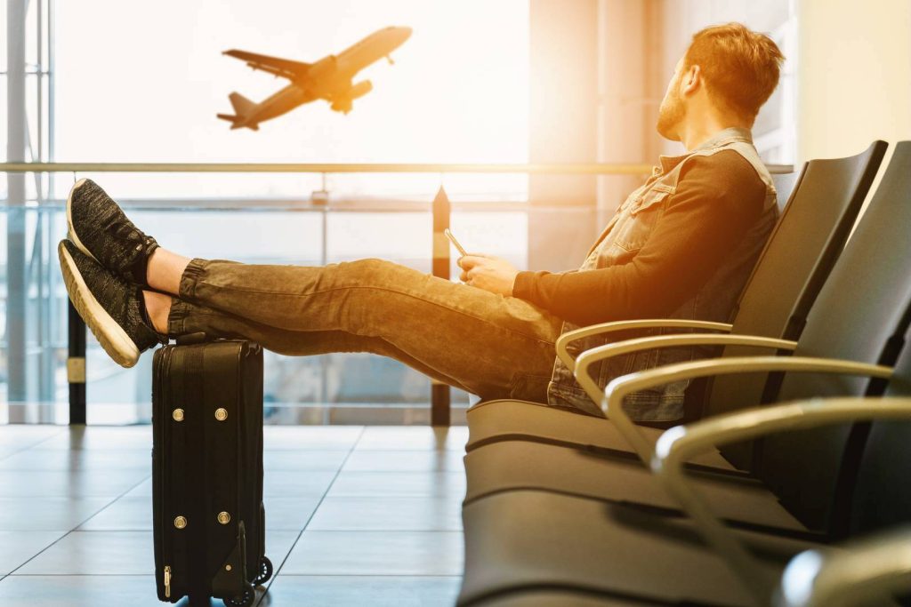 Man Relaxing at Airport with Feet on Suitcase Watching Plane