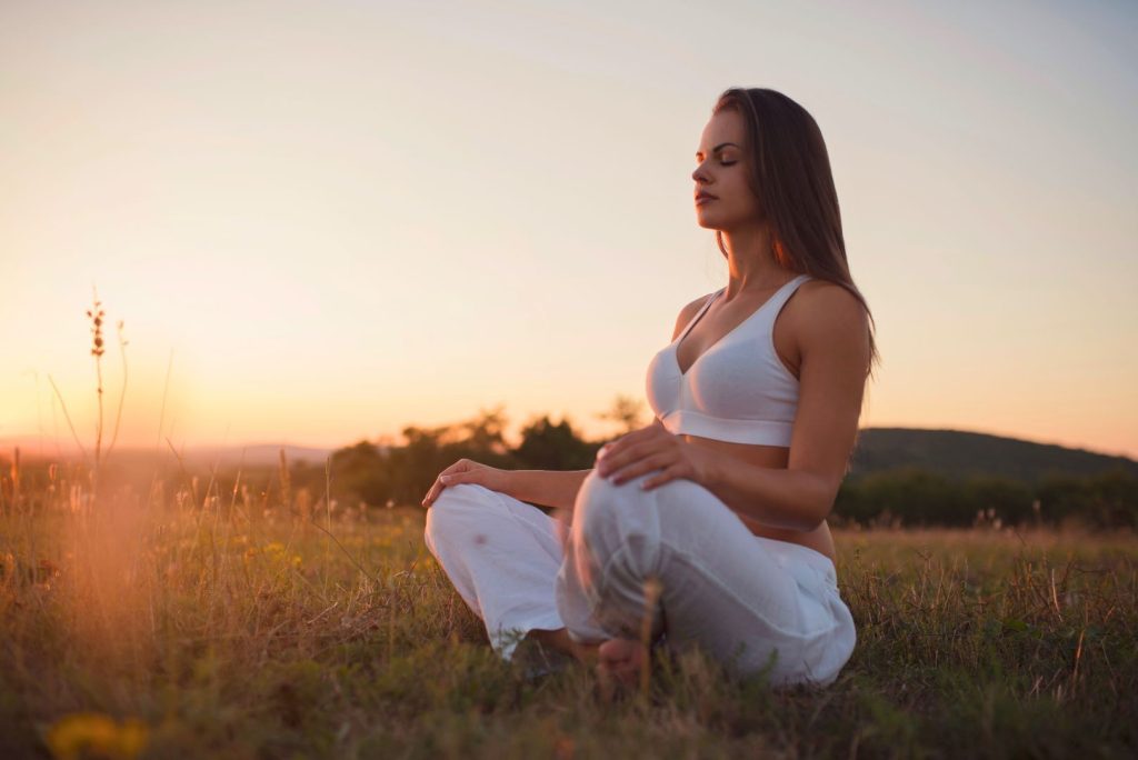 Beautiful Woman Sitting in a Field Meditating Mindfulness