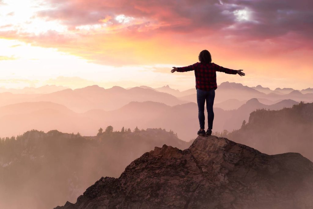 Woman on Top of Mountain with Arms Wide Open