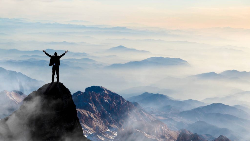 Man Standing at the Top of a Mountain Having Success