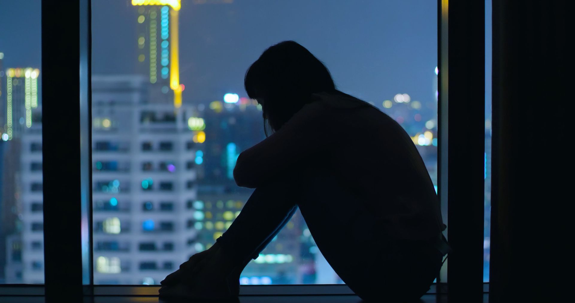 Woman Sitting on Windowsill Depressed and Sad with City View