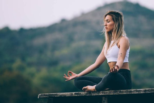 Calm Woman Meditating with Hill in Background