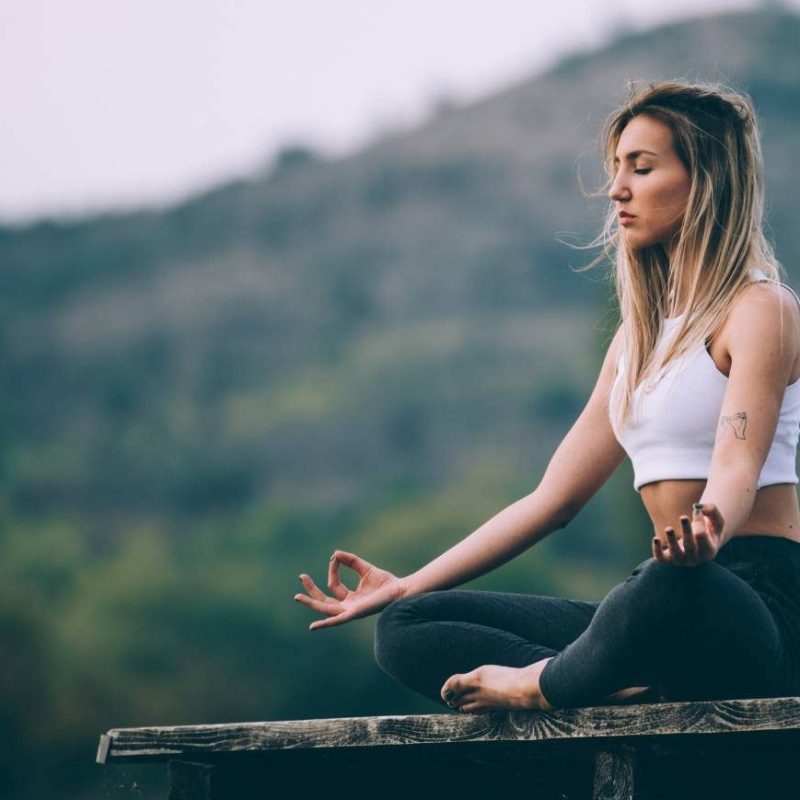 Calm Woman Meditating with Hill in Background