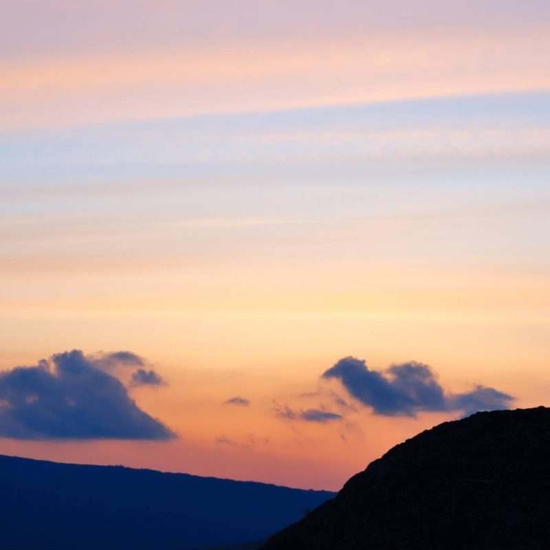 Silhouette of a Man Meditating on a Hill with Sunset Background