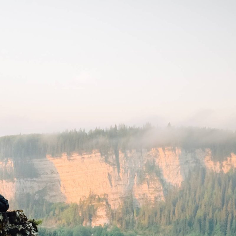 Man Sitting on Rock Meditating with View of Mountain