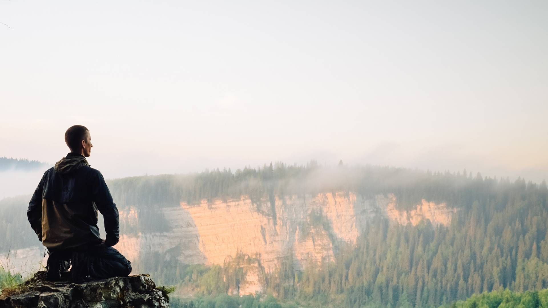 Man Sitting on Rock Meditating with View of Mountain