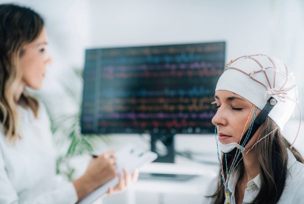 Woman Meditating with Scientist Measuring Brainwaves with EEG Helmet